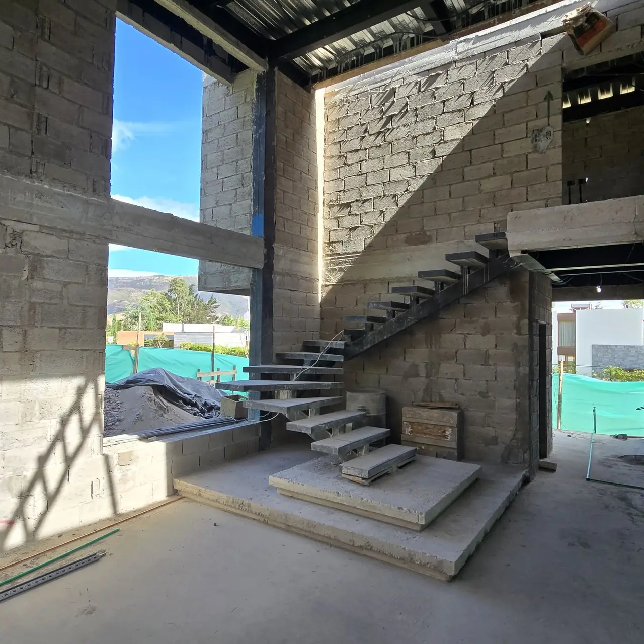 Escalera flotante y muro de piedra en casa construida por PIVOT Constructores en Quito